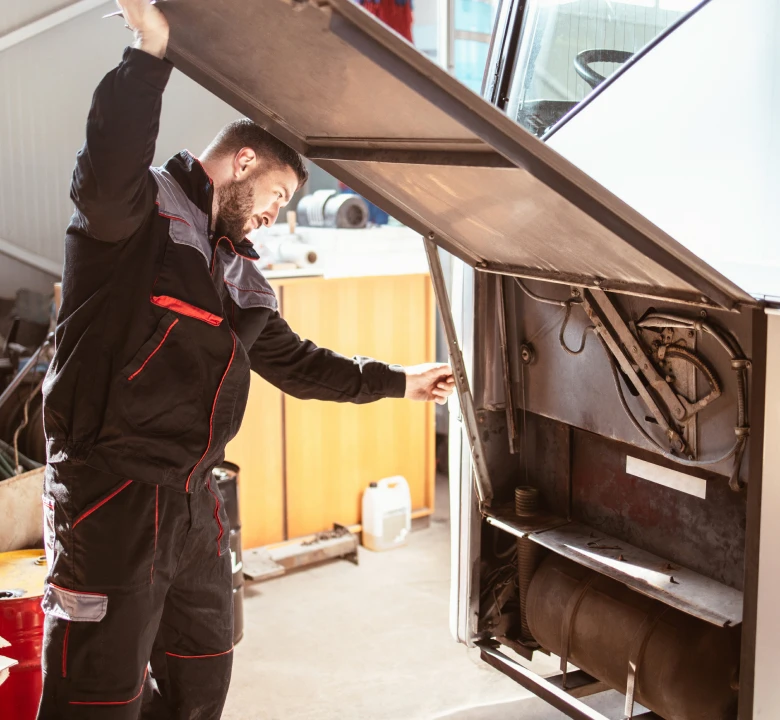 Mechanic inspecting vehicle engine compartment